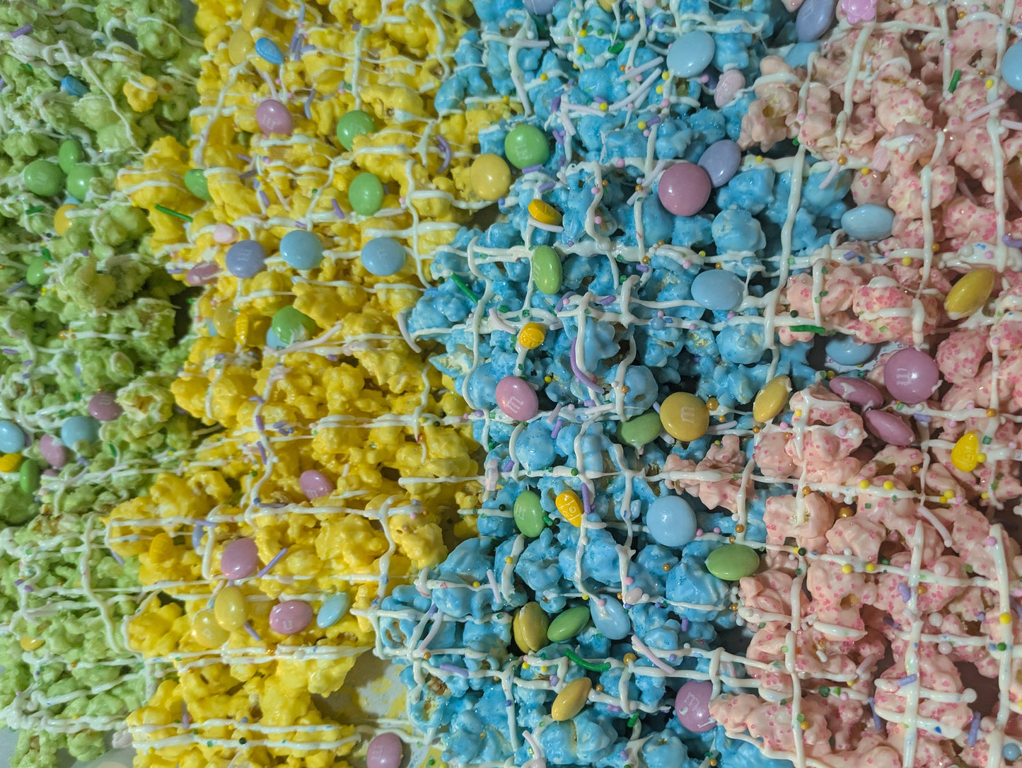 Colorful popcorn treats with white chocolate drizzle on a white plate